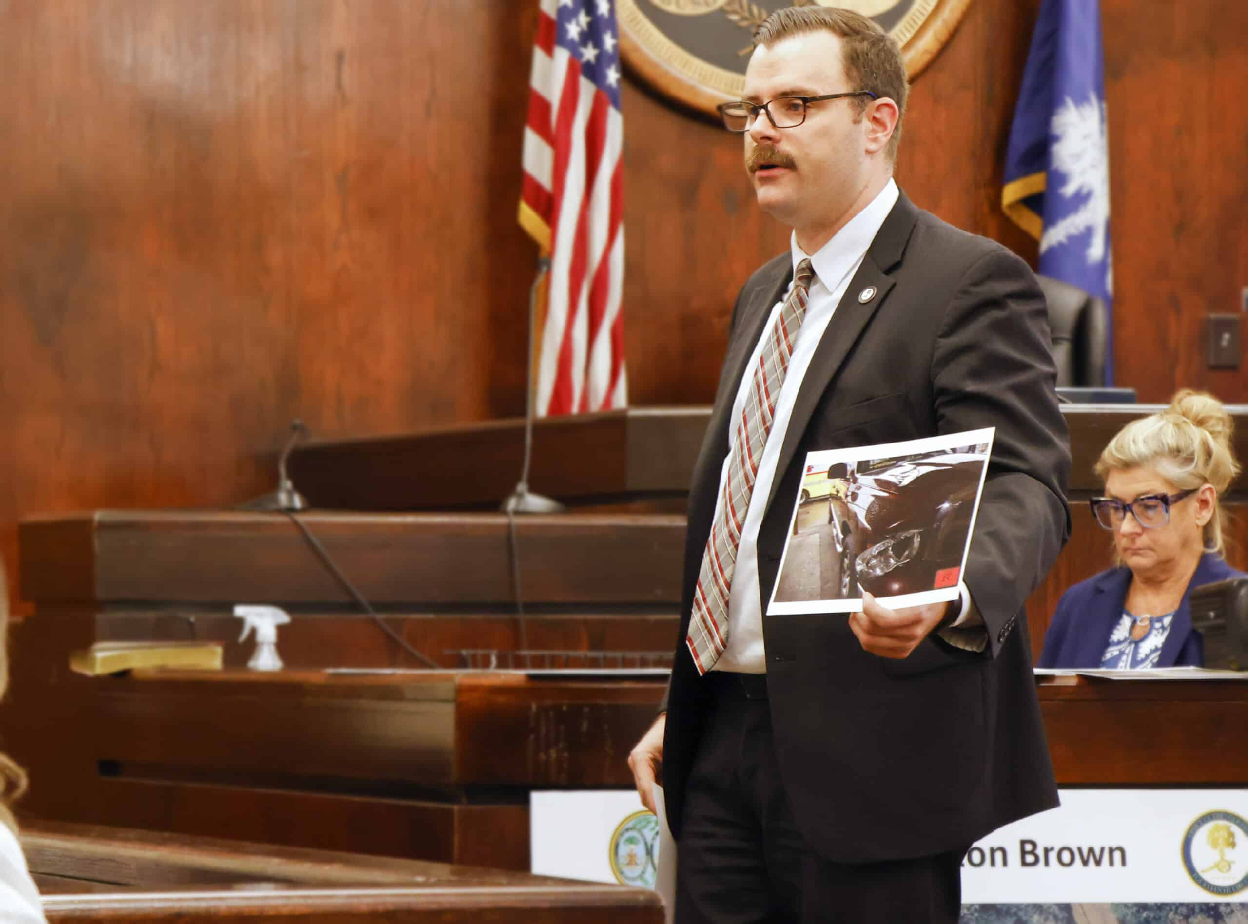 Assistant Solicitor Jared Shedd shows the jury a photo of damage to the headlight of a vehicle driven by defendant Clinton Brown sustained in a hit-and-run collision that killed pedestrian Rediedre Holmes in 2019.