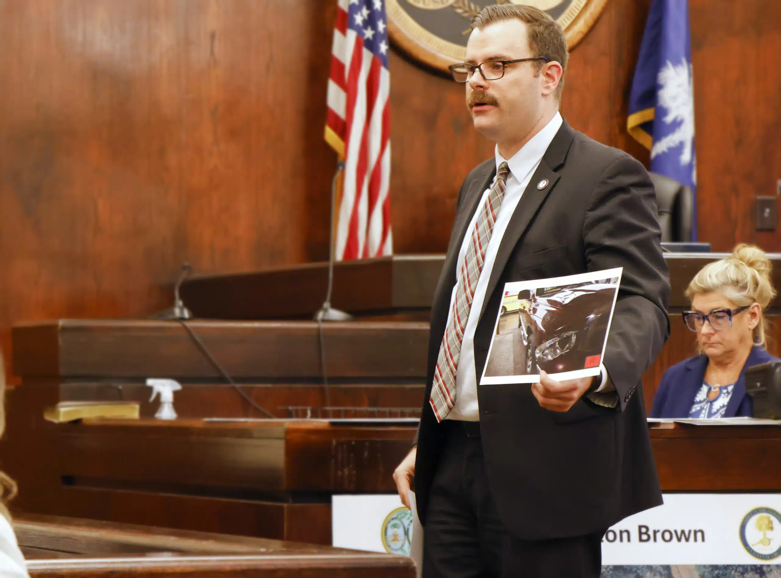 Assistant Solicitor Jared Shedd shows the jury a photo of damage to the headlight of a vehicle driven by defendant Clinton Brown sustained in a hit-and-run collision that killed pedestrian Rediedre Holmes in 2019.
